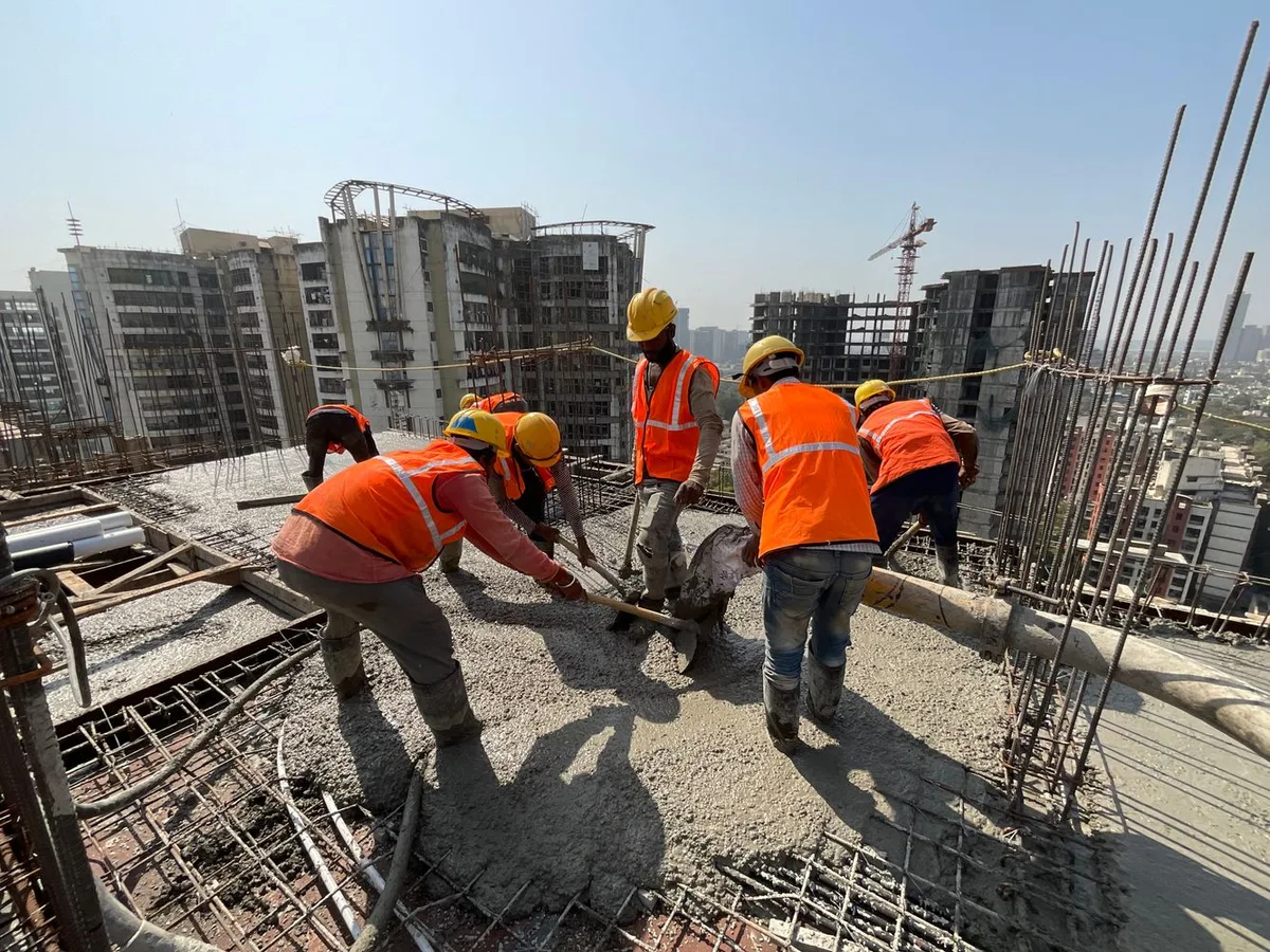 Construction workers placing concrete on a reinforced floor slab.